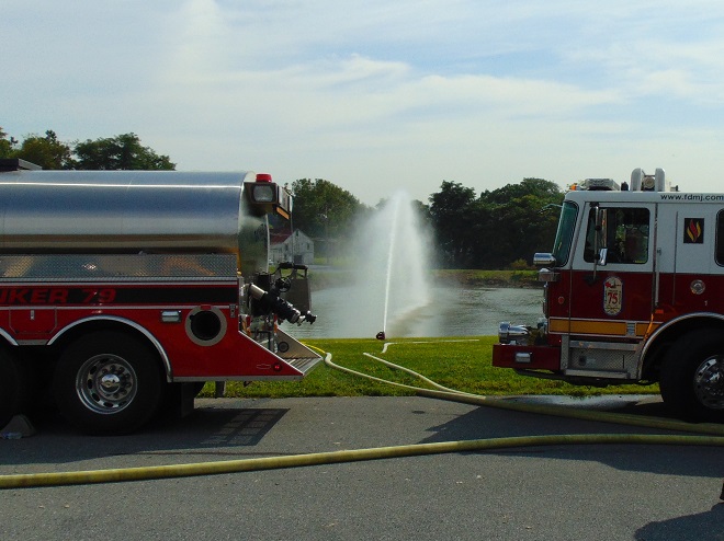 A tanker/tender in nurse configuration supplies water to a fire engine pumping to a portable master stream device.