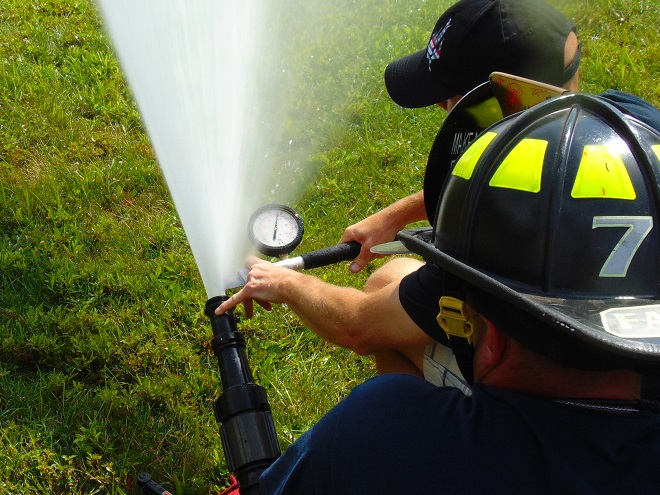Measuring nozzle pressure of a fire stream using a pitot tube and gauge.